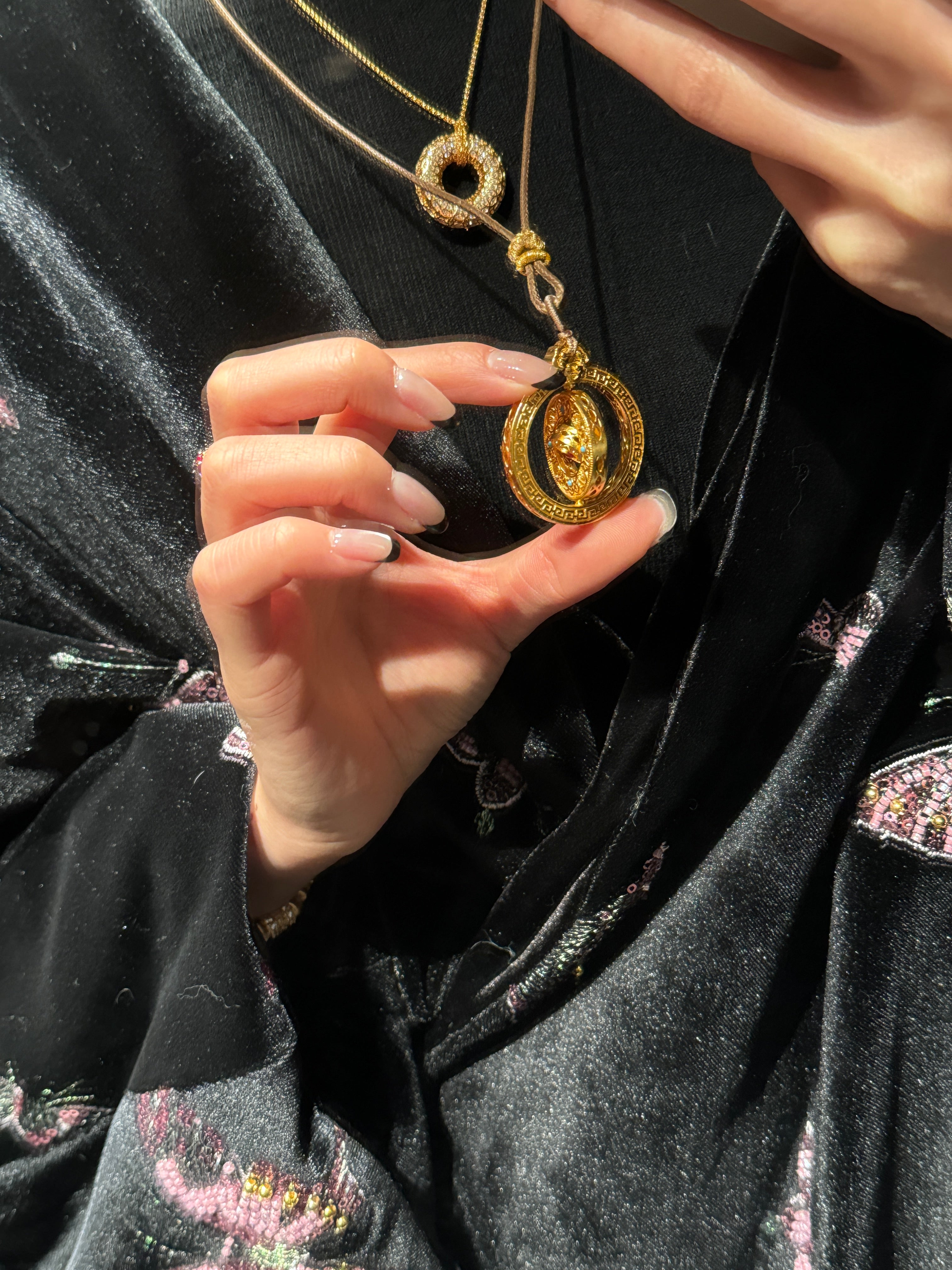 Elysian Jewelry 925 silver with 18k plated gold necklace with a pendant held by a hand against a dark background