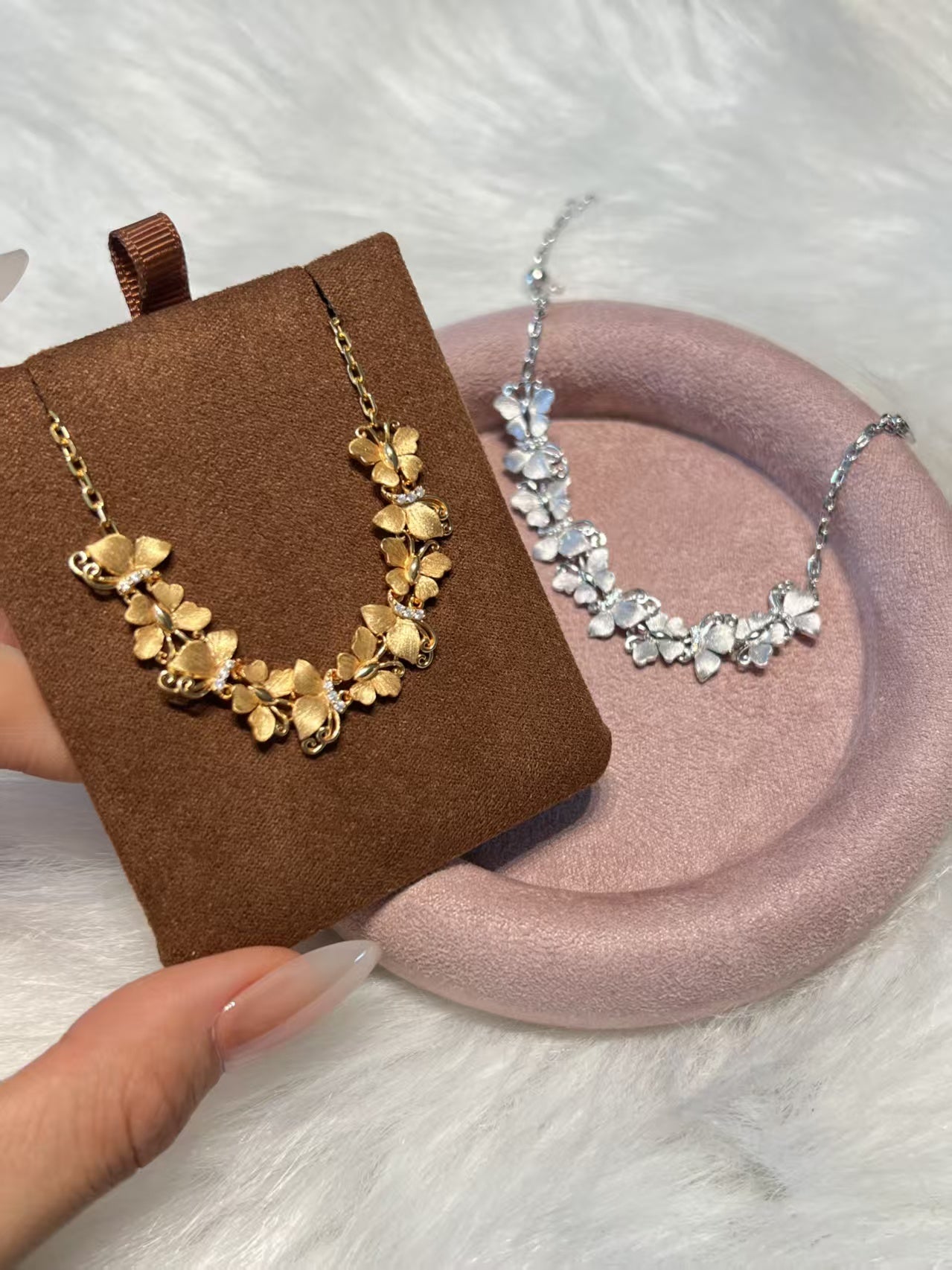 Elysian Jewelry 925 silver and 18k gold-plated floral necklaces on display with a hand holding the gold necklace.