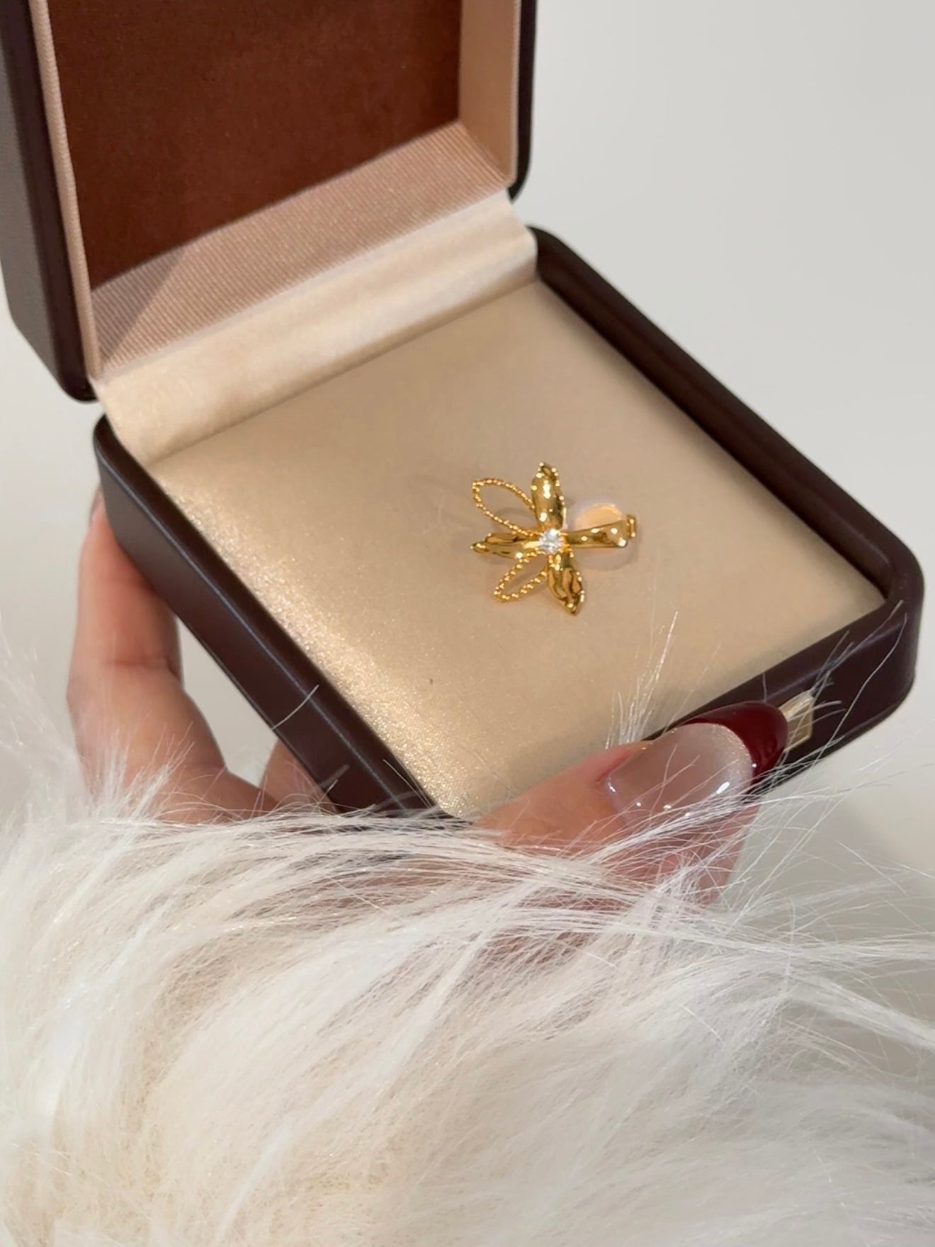 Elysian Jewelry 925 silver with 18k plated gold butterfly-shaped earring in a jewelry box held by a hand with white fur background