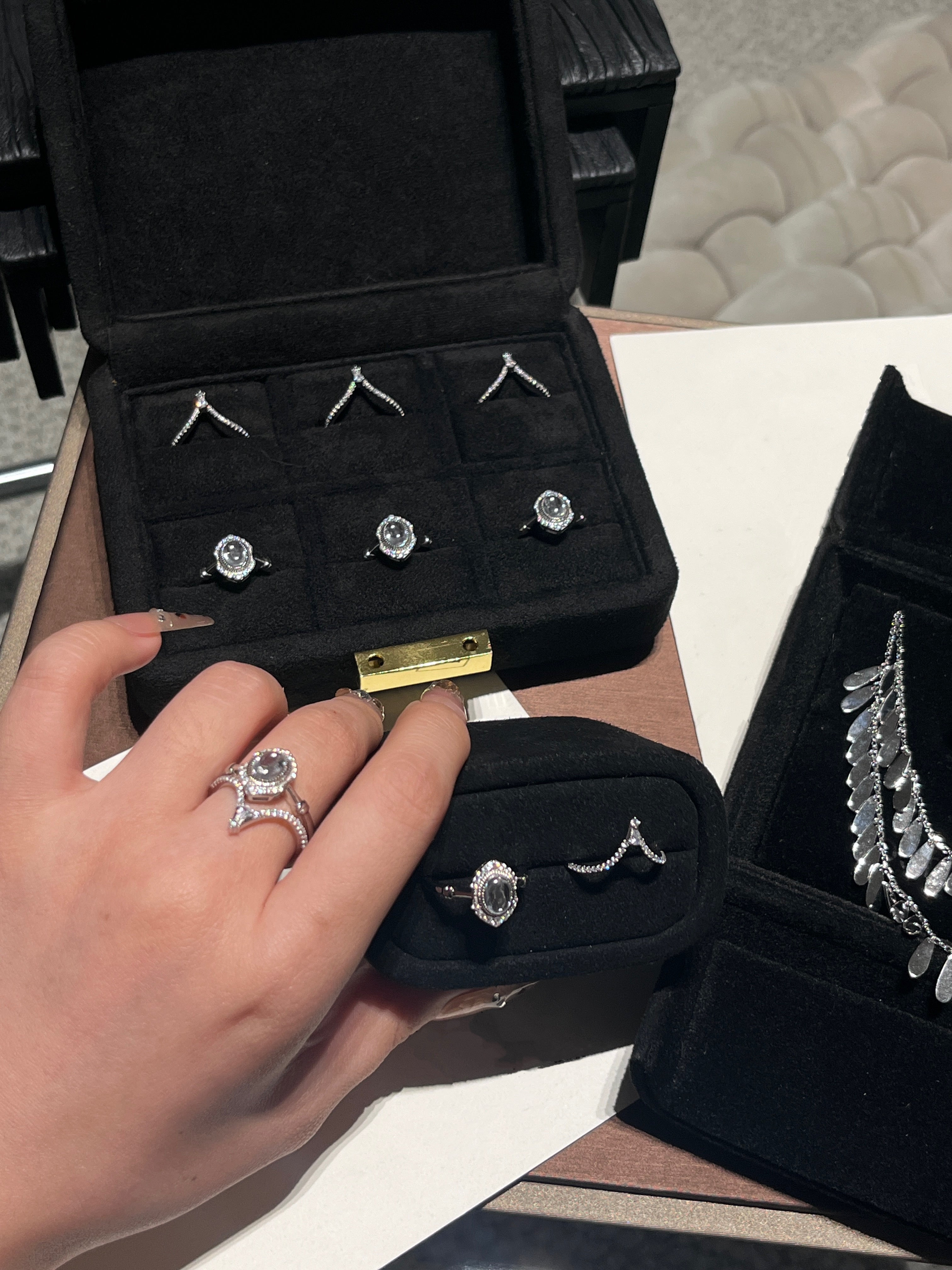 Elysian Jewelry 925 silver jewelry set including rings and earrings in a black jewelry box with a hand holding one of the rings.