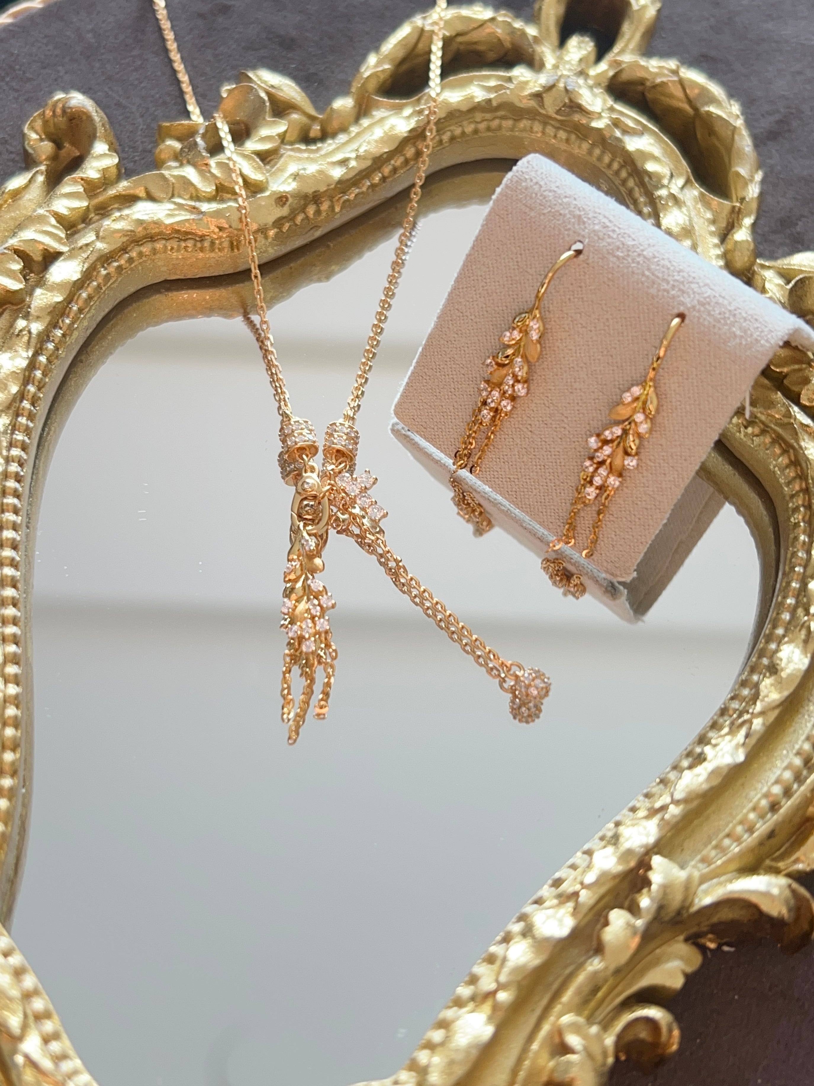 Elysian Jewelry 925 Silver with 18k plated gold jewelry set including necklace and earrings displayed against a decorative gold frame.