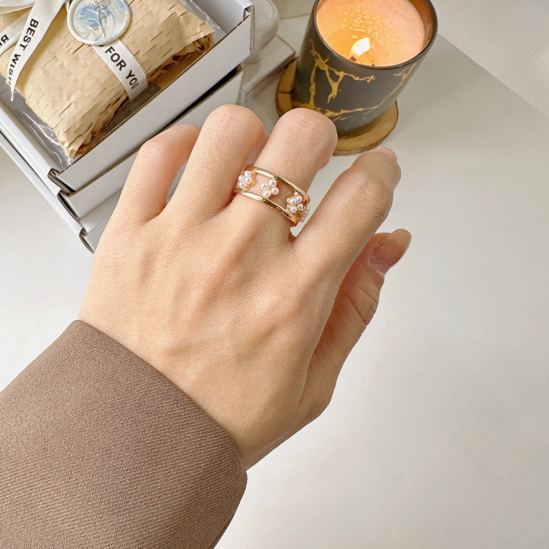 Elysian jewelry gold ring with a decorative band, on a light surface with a candle and gift box in the background.