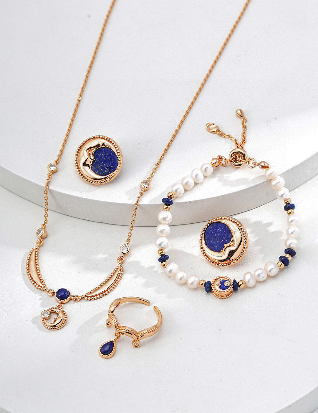 Elysian Jewelry 925 silver with 18k plated gold and blue jewelry set including necklace, bracelet, and earrings on a white surface.